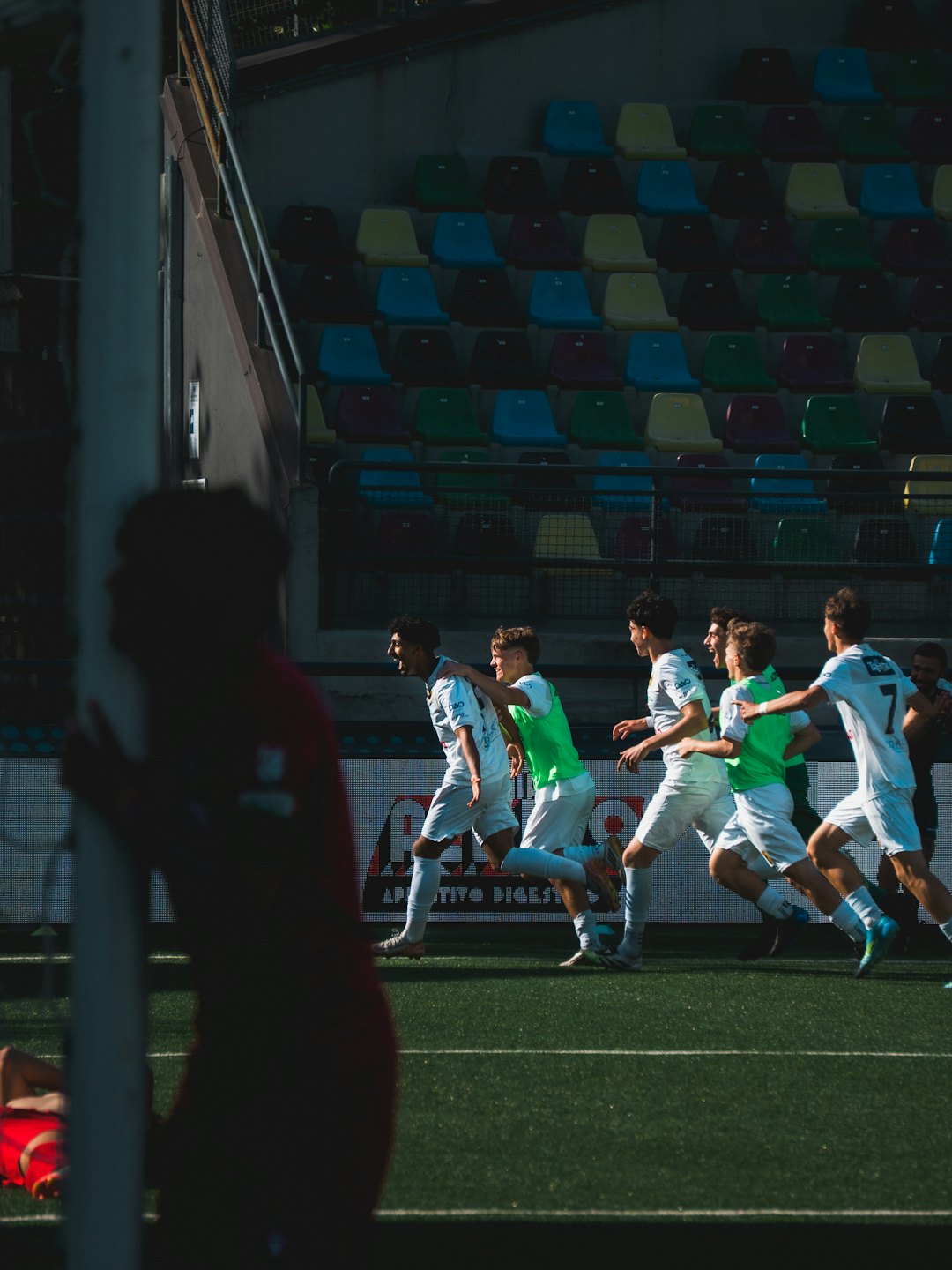 Voetballers in witte en groene tenues juichen op een veld.