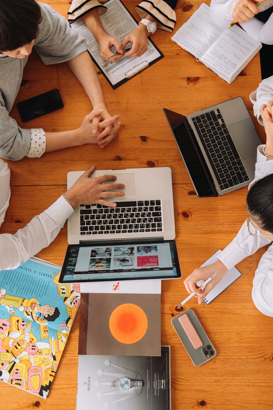 Professionals die samenwerken rond een tafel met laptops en documenten.