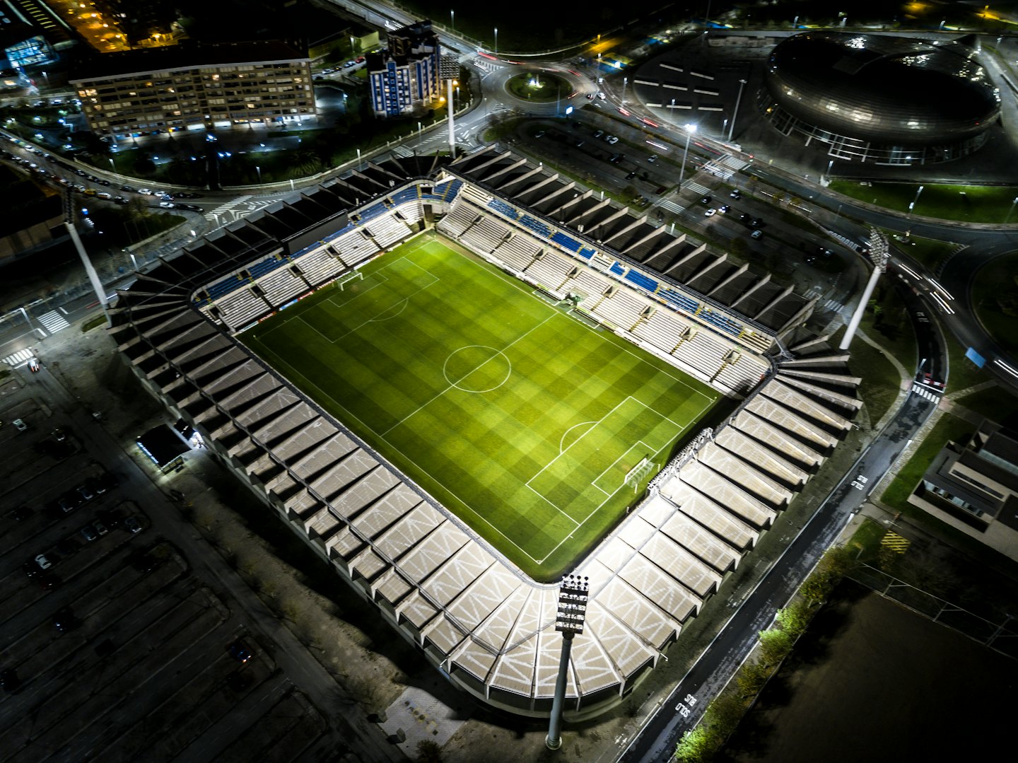 Voetbalstadion 's nachts met gloeiend groen veld.